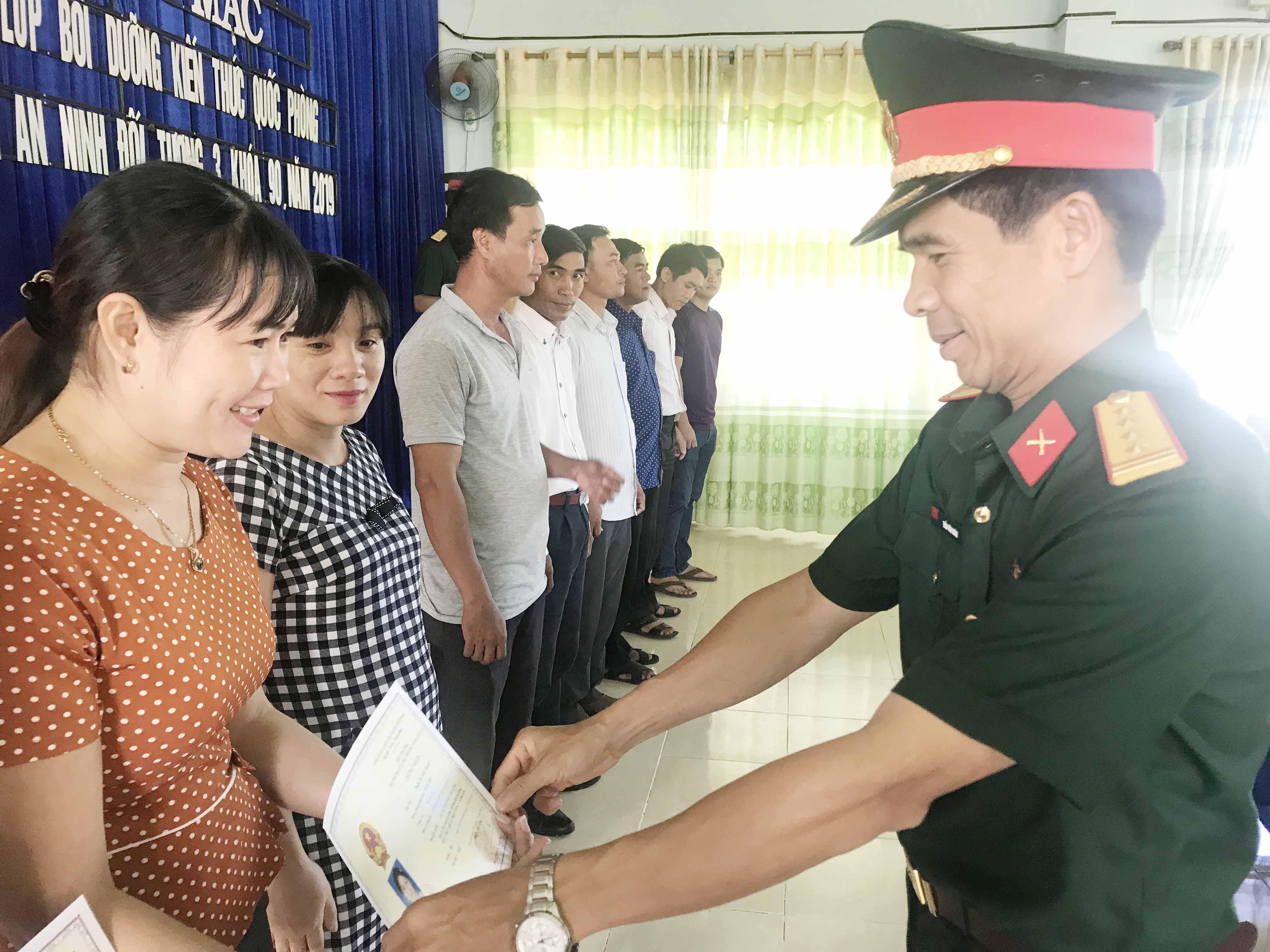 Đại tá Trần Văn Hoàn-Chính ủy trường Quân sự tỉnh trao giấy chứng nhận cho các học viên. Ảnh: Nguyễn Sang