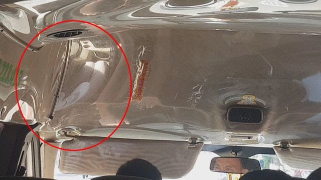 Hình ảnh hành khách bị bắt ngồi bên trái tài xế được phản chiếu lên lớp nilon trên nóc xe.