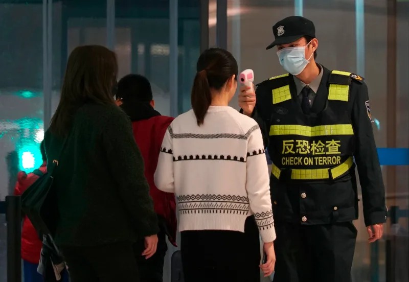 Nhân viên sân bay sử dụng máy đo nhiệt để kiểm tra hành khách rời khỏi sân bay quốc tế Thiên Hà tại TP Vũ Hán (Ảnh: AP)