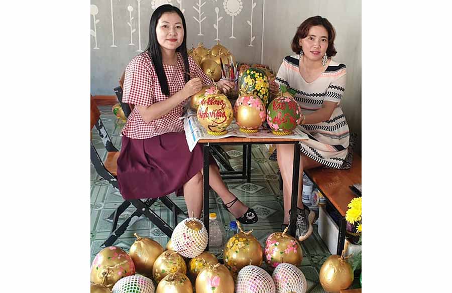     Chị Phan Kim Thanh (bìa trái)  và chị Lê Thị  Kim Thúy  đang vẽ thư pháp trên quả dừa.  Ảnh: V.M.H
