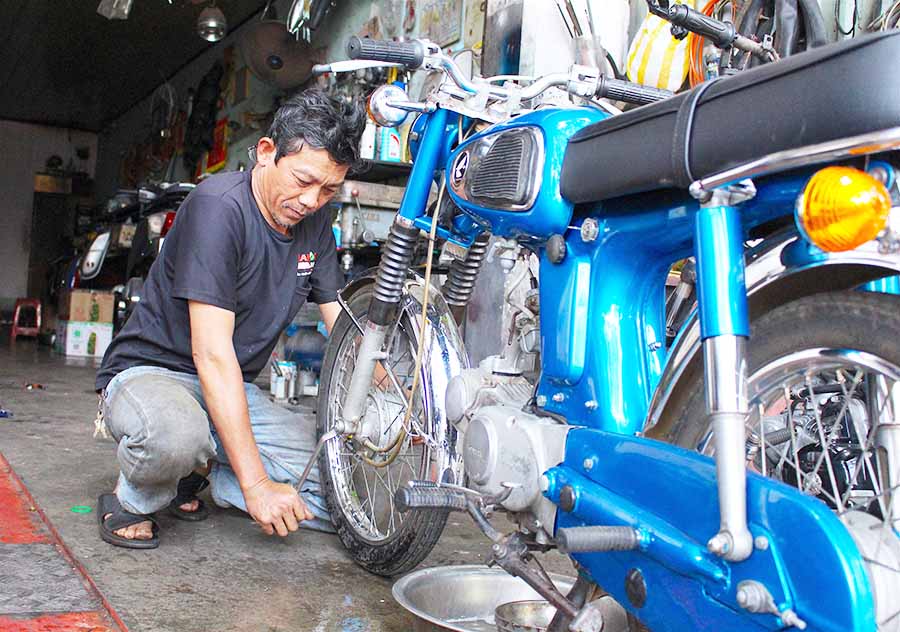  Ông Lê Nguyễn Bửu Khôi miệt mài sửa một chiếc xe Honda cổ cho khách. Ảnh: M.T