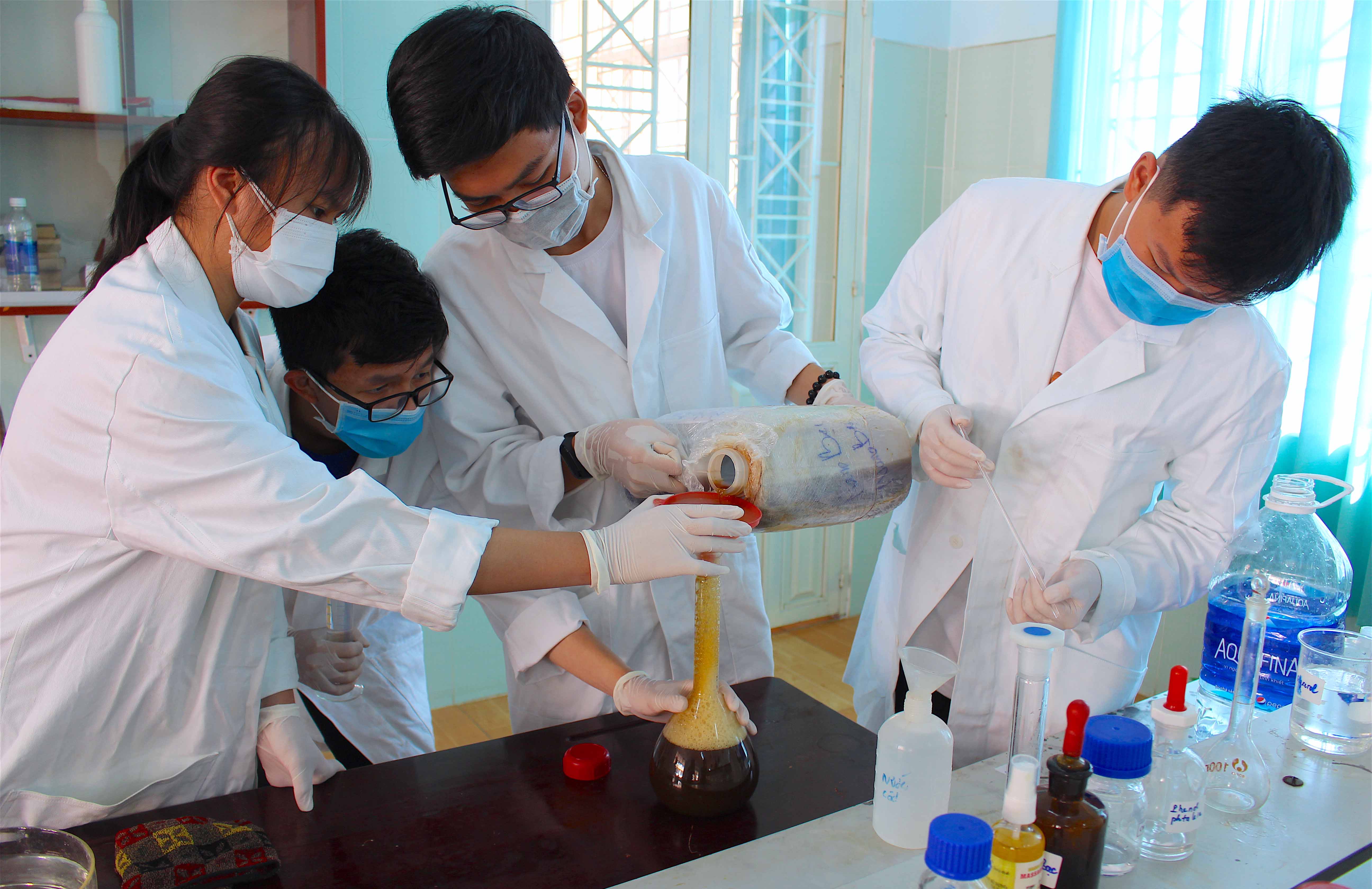 Các em học sinh đang pha loãng dung dịch nano bạc với nước trước khi tiến hành pha chế. Ảnh: Mộc Trà