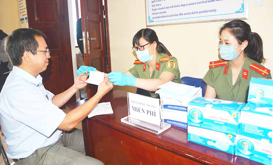 Cán bộ Phòng xuất nhập Cảnh, Công an tỉnh phát khẩu trang miễn phí cho người dân đến giải quyết công việc tại đơn vị.