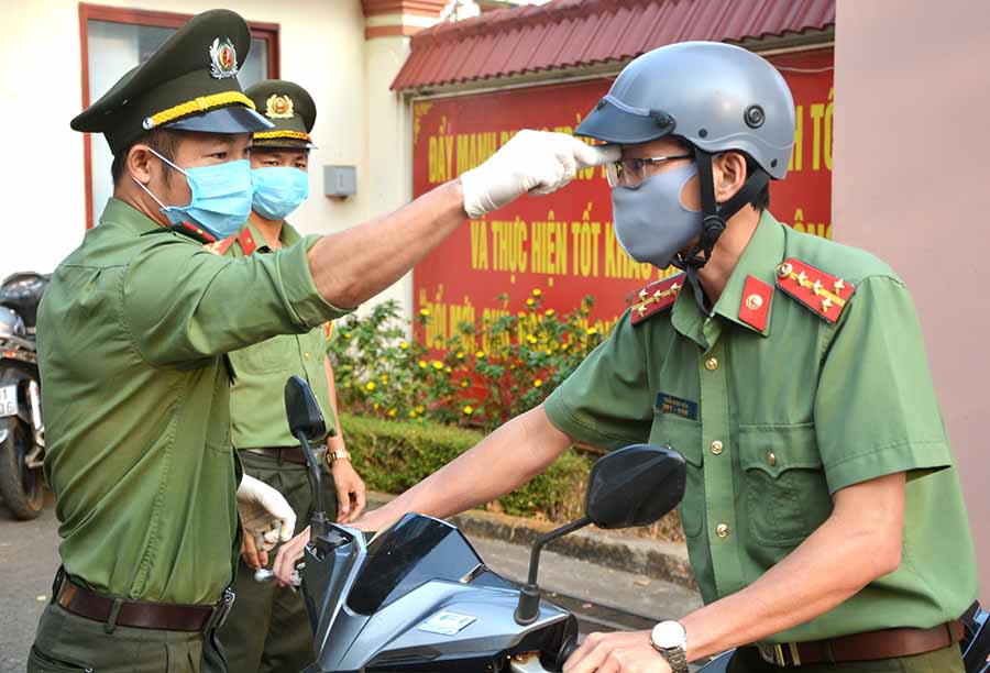 Tổ công tác Bệnh xá Công an tỉnh kiểm tra thân nhiệt cho cán bộ, chiến sĩ trước giờ làm việc. Ảnh: Hữu Trường