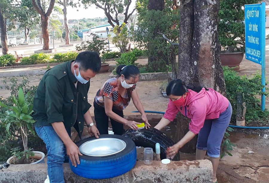Các thầy cô giáo Trường Tiểu học Kim Đồng (huyện Đức Cơ) đang rửa lốp xe để chuẩn bị triển khai mô hình bồn rửa tay cho học sinh. Ảnh: Hồng Thi