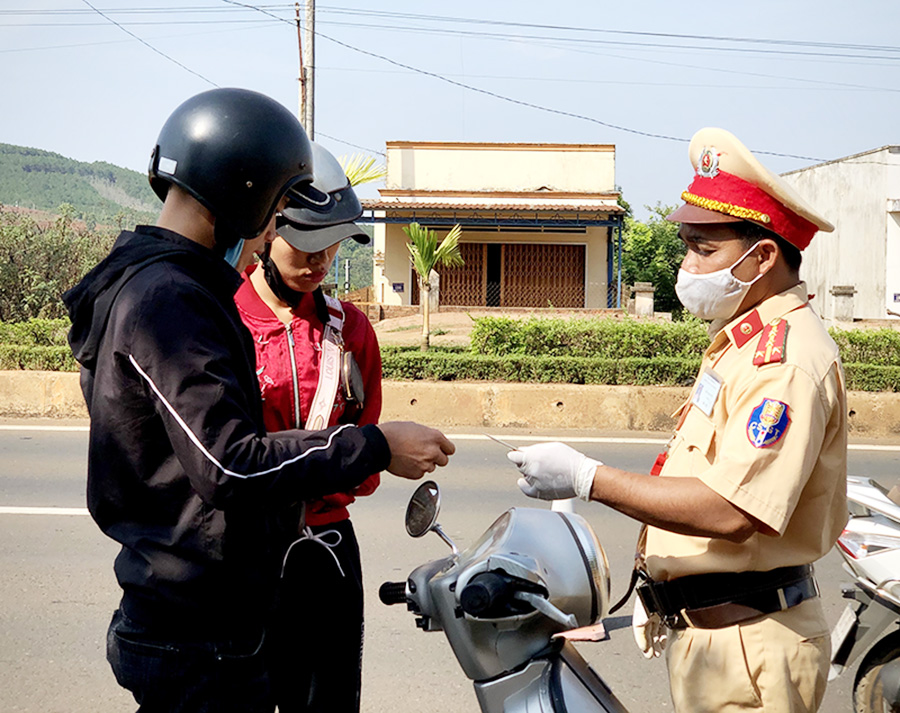  Cảnh sát Giao thông Công an tỉnh kiểm tra giấy tờ 1 người điều khiển xe máy tham gia giao thông trên quốc lộ 19. Ảnh: L.H