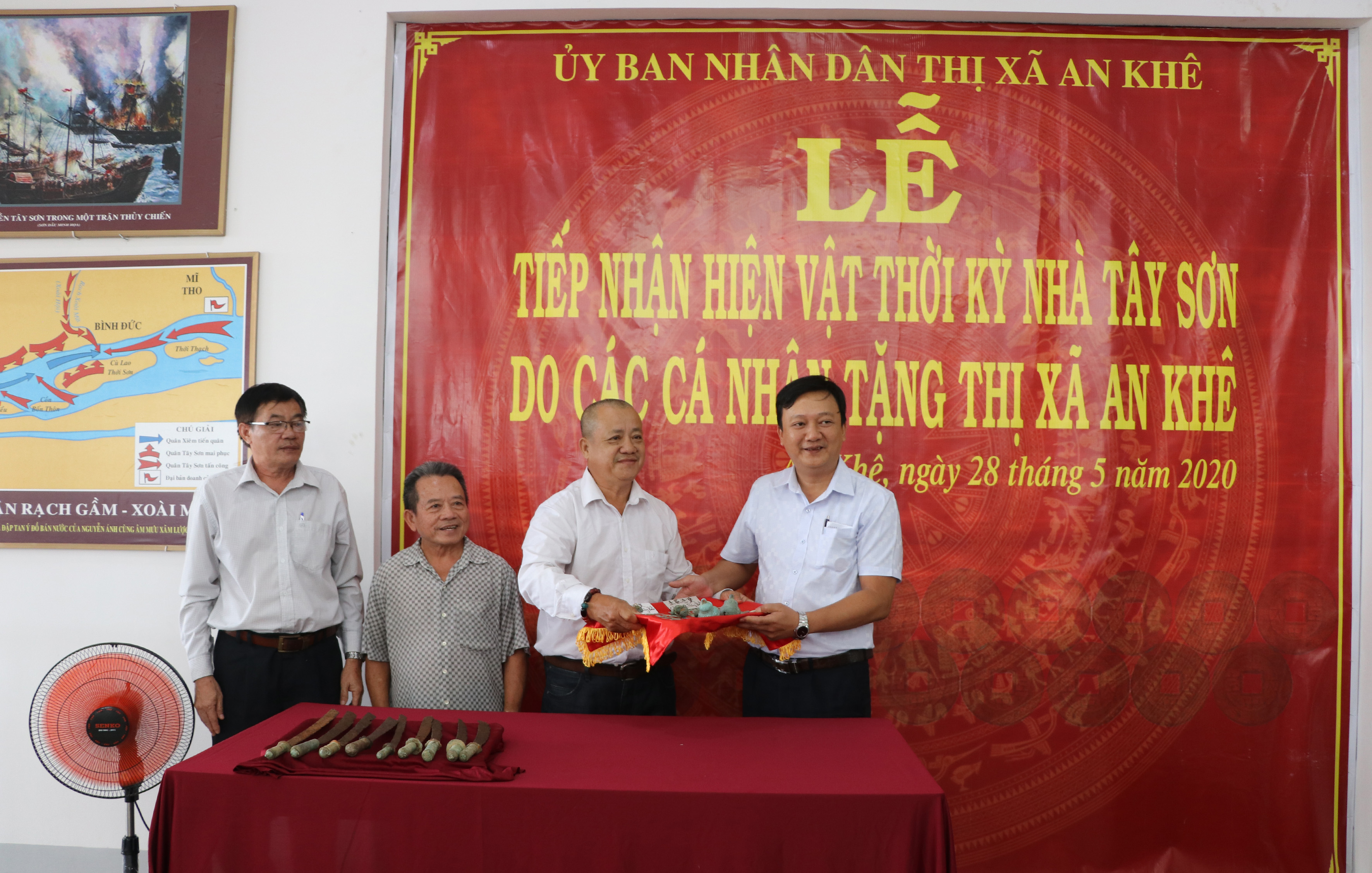 Ông Lâm Dũ Xênh (thứ 3 bên trái; huyện Bình Sơn, tỉnh Quảng Ngãi) trao tặng 99 đồng tiền và 8 cái lục lạc đồng thời kỳ nhà Tây Sơn cho thị xã An Khê. Ảnh: Ngọc Minh