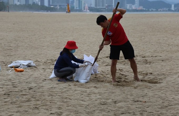 Anh Trí cùng vợ xúc cát bên bờ biển Nha Trang để về giằng chống nhà, chiều 9/11. Ảnh: Xuân Ngọc.