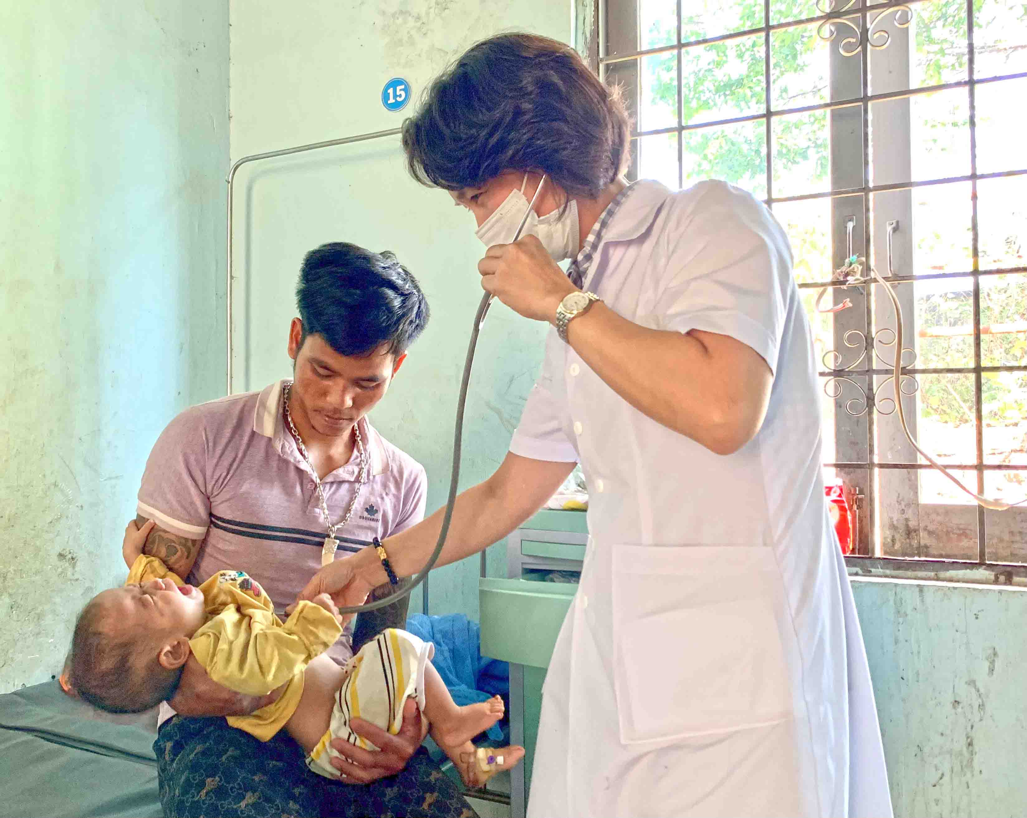 Bác sĩ Khoa Nội-Nhi-Nhiễm (Trung tâm Y tế huyện Mang Yang) thăm khám cho bệnh nhi bị viêm phổi trên nền suy dinh dưỡng. Ảnh: Như Nguyện