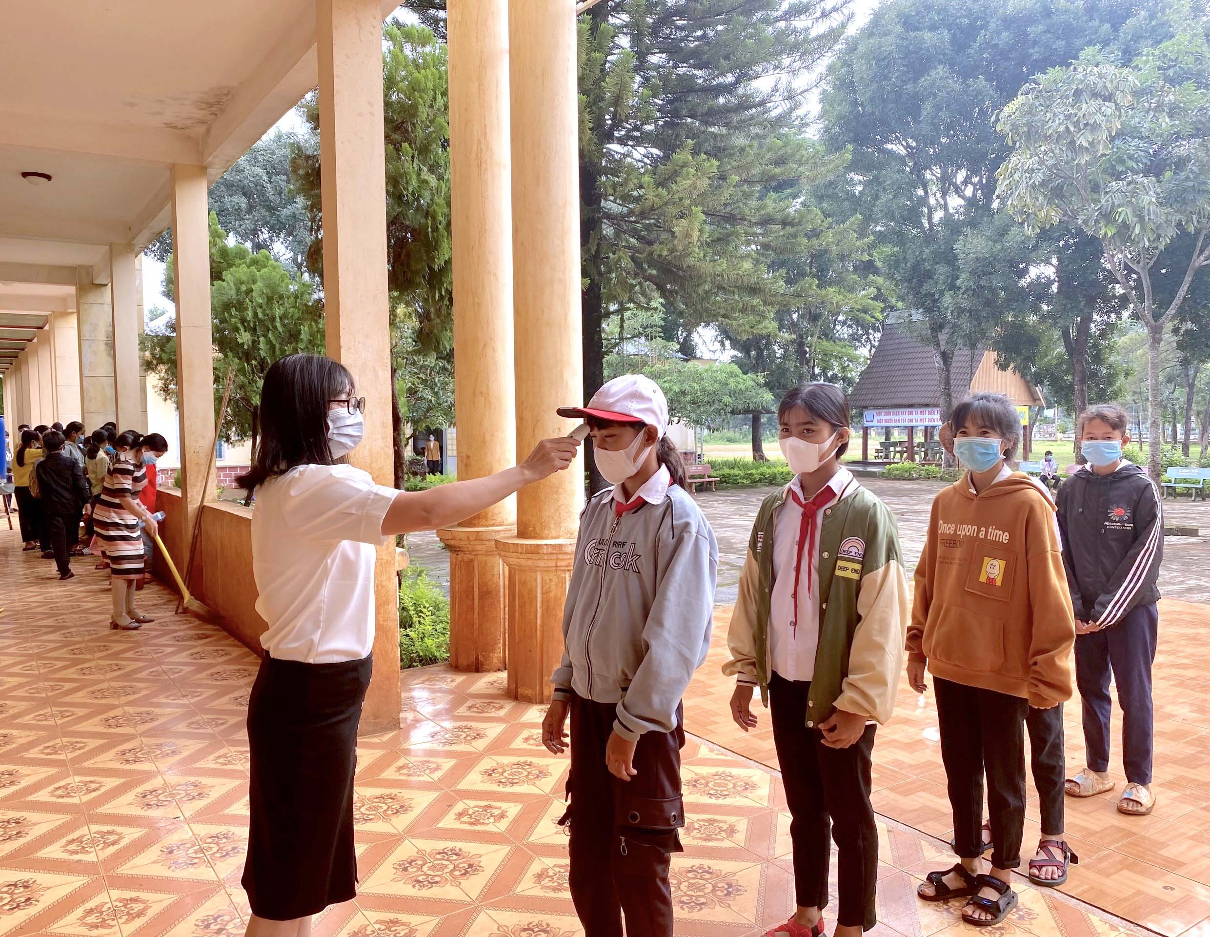 Giáo viên Trường THCS xã Ia Ka (huyện Chư Păh) đo thân nhiệt học sinh trước khi vào lớp học. Ảnh: Ngọc Thu