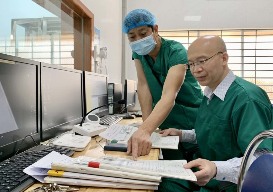 Tiến sĩ Hoàng Văn-Phó Giám đốc Bệnh viện Tim Hà Nội (người ngồi) trao đổi chuyên môn với bác sĩ CKII Trần Kế Toán-Trưởng khoa Tim mạch (Bệnh viện Đa khoa tỉnh) trước khi triển khai chụp mạch cho bệnh nhân. Ảnh: Như Nguyện