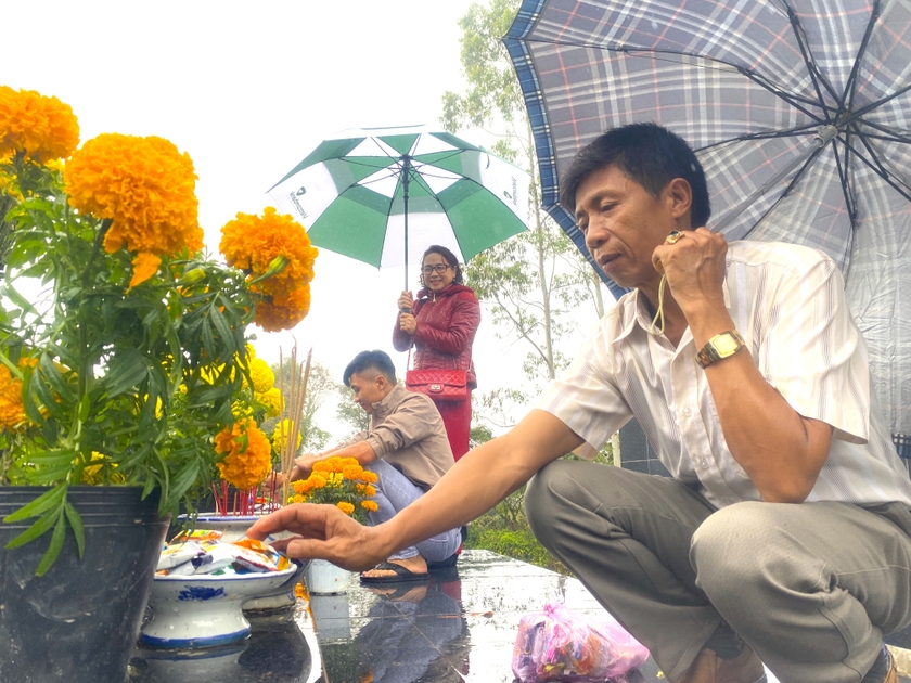 Ông Lê Văn Tài (tổ 5, phường Tây Sơn, thị xã An Khê) cùng vợ con viếng mộ ông bà, dâng hoa, bánh kẹo, cầu mong năm mới vạn sự an lành. Ảnh: Ngọc Minh
