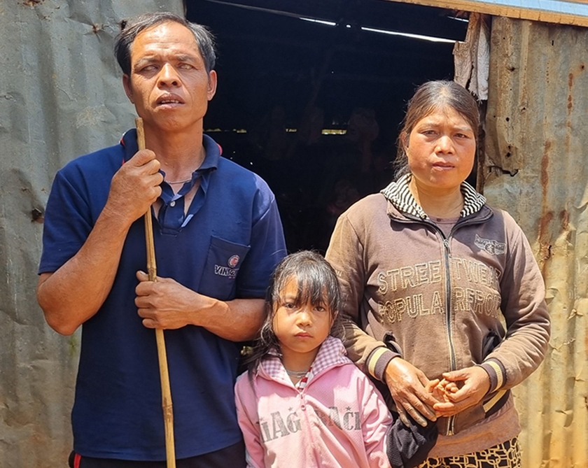 Chị Rơ Châm Thủy cùng người chồng bị mù và con gái nhỏ trước căn nhà tạm, xập xệ, xuống cấp. Ảnh: Khánh Phong