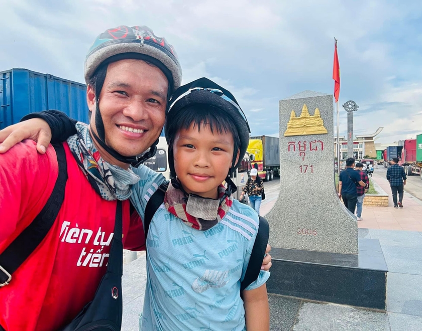 Hai bố con em Nông Quang Anh chụp hình lưu niệm tại Cửa khẩu Quốc tế Mộc Bài trên hành trình xuyên các nước Đông Dương và Thái Lan (ảnh nhân vật cung cấp).