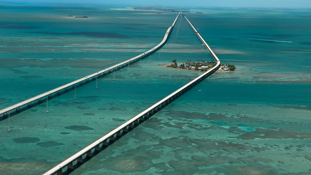Đường cao tốc Overseas ở Florida chạy từ Key Largo đến Key West, trải dài hơn 177 km và qua 42 cây cầu. Cầu Seven Mile là điểm nhấn, với làn nước ngọc lam ở cả hai bên. Người lái xe đi qua các rạn san hô, làng chài và bãi biển. Mùa đông và mùa xuân là thời điểm đẹp nhất, thường được mô tả như một con đường cao tốc nổi trên biển. ẢNH: ALAMY