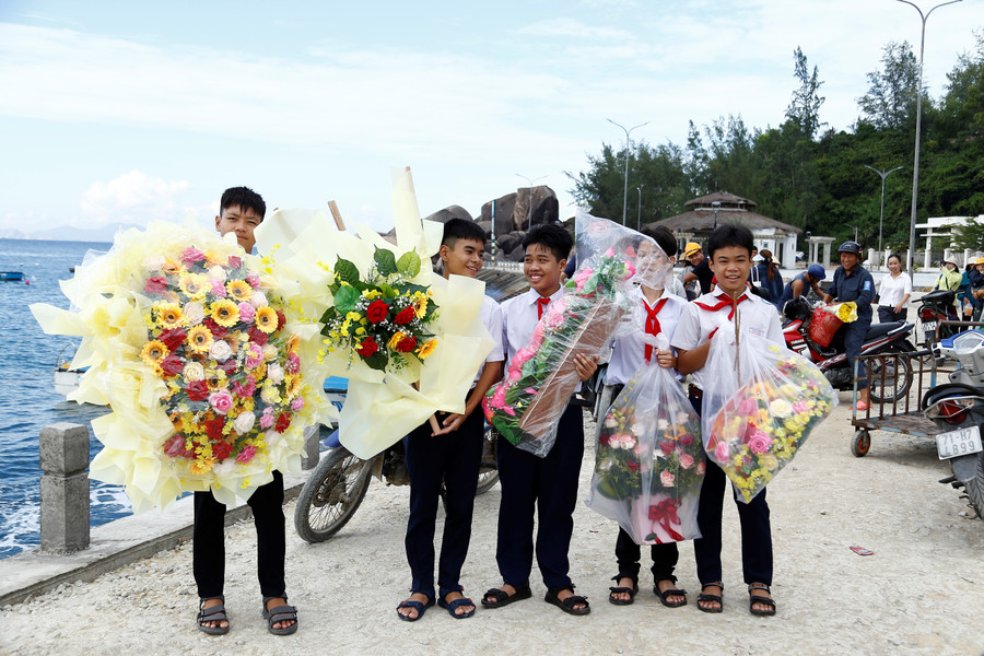 Các học sinh phụ giúp giáo viên ra bến thuyền nhận hoa từ đất liền gửi ra phục vụ lễ khai giảng. Ảnh: H.P mg-2149.jpg